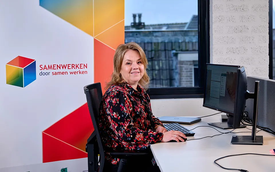 Een mevrouw achter haar bureau dat naar de fotograaf kijkt